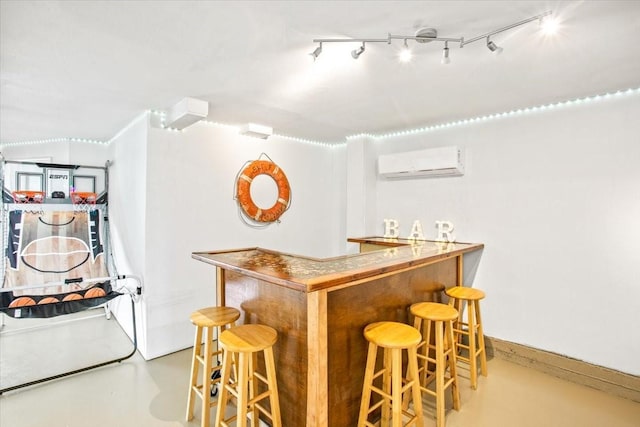 bar featuring concrete flooring, a wall unit AC, baseboards, a bar, and rail lighting