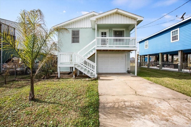 coastal inspired home featuring a porch, an attached garage, stairs, driveway, and a front lawn