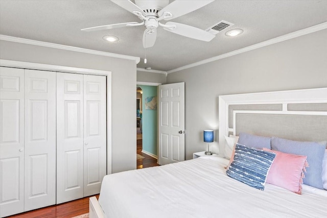 bedroom featuring a closet, visible vents, ornamental molding, a ceiling fan, and wood finished floors