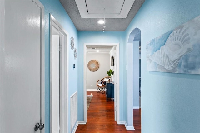 hall featuring attic access, baseboards, and wood finished floors