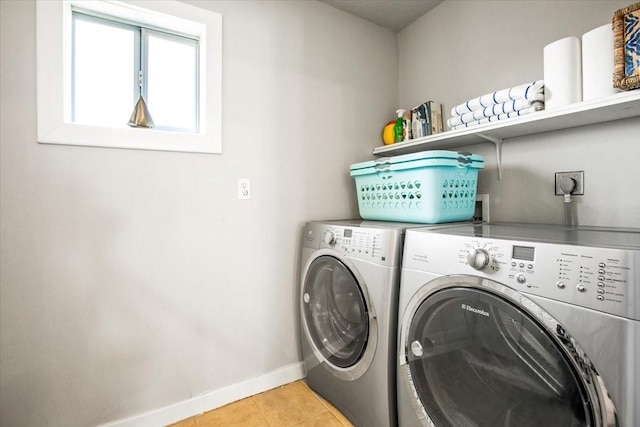 clothes washing area with washer and dryer, laundry area, baseboards, and light tile patterned floors