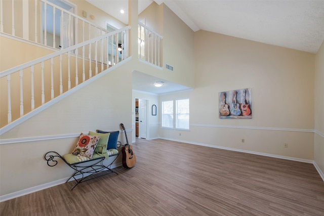 living area featuring high vaulted ceiling, visible vents, baseboards, and wood finished floors