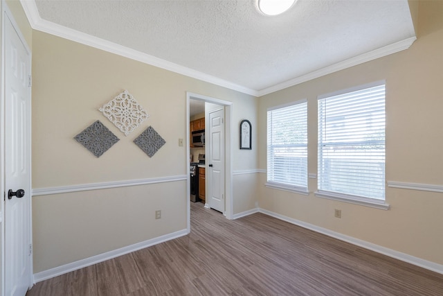 empty room featuring crown molding, a textured ceiling, and wood finished floors