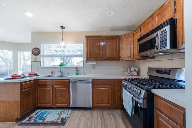 kitchen with a wealth of natural light, appliances with stainless steel finishes, brown cabinetry, and a sink