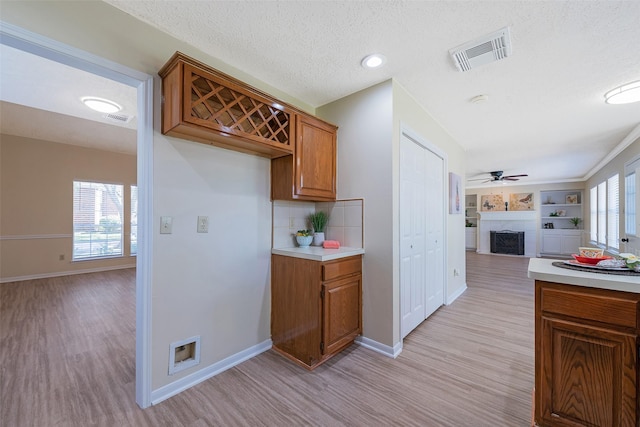 kitchen with brown cabinets, a fireplace, light countertops, visible vents, and open floor plan