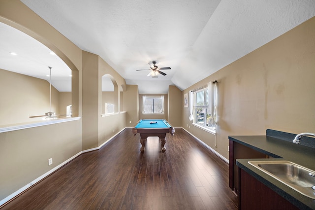 recreation room featuring baseboards, dark wood finished floors, a ceiling fan, lofted ceiling, and a sink