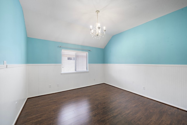 spare room featuring lofted ceiling, a chandelier, hardwood / wood-style floors, and wainscoting