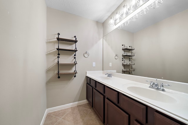 full bath featuring baseboards, double vanity, a sink, and tile patterned floors