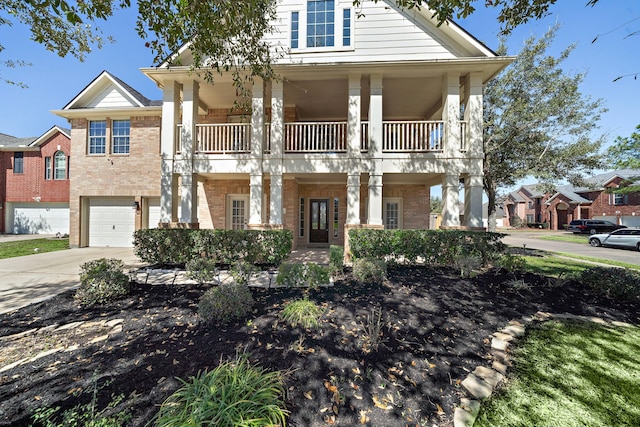 view of front facade with a garage, brick siding, driveway, and a balcony