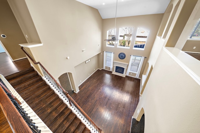 foyer featuring a fireplace, stairway, ceiling fan, high vaulted ceiling, and hardwood / wood-style flooring