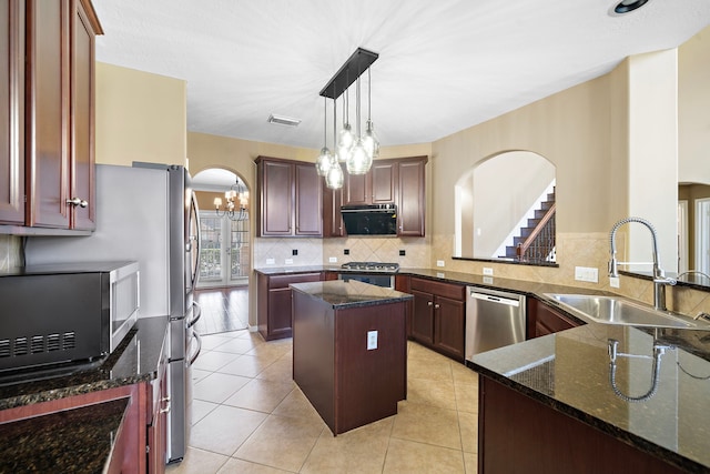 kitchen featuring arched walkways, stainless steel appliances, visible vents, a sink, and a kitchen island