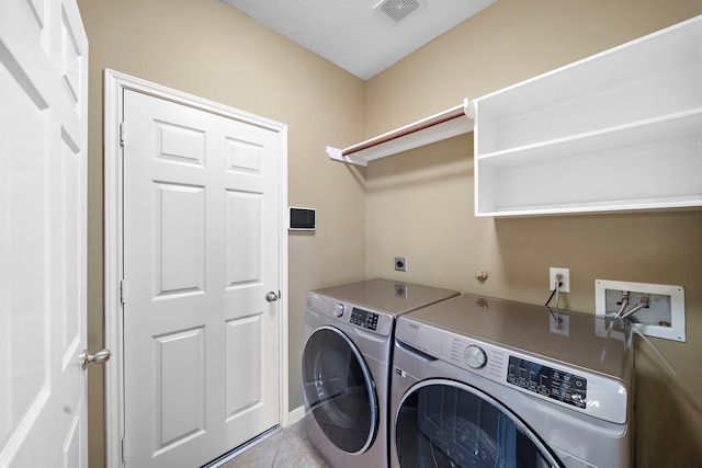 washroom featuring light tile patterned floors, laundry area, washing machine and clothes dryer, and visible vents