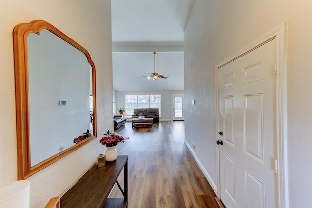 corridor with lofted ceiling, wood finished floors, and baseboards