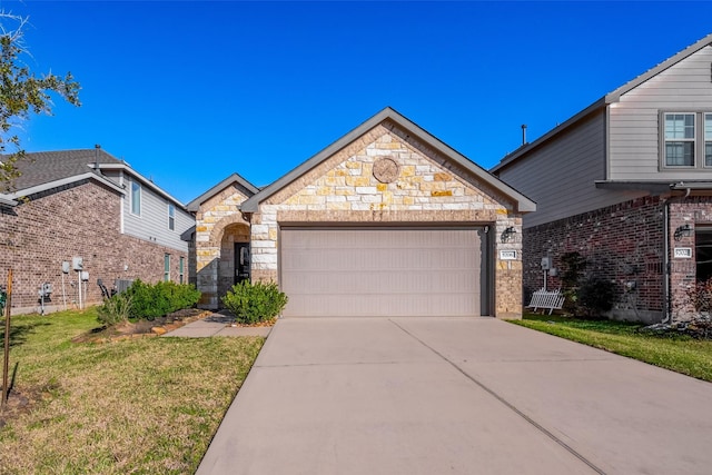 view of front of property with concrete driveway, an attached garage, a front yard, central AC, and stone siding