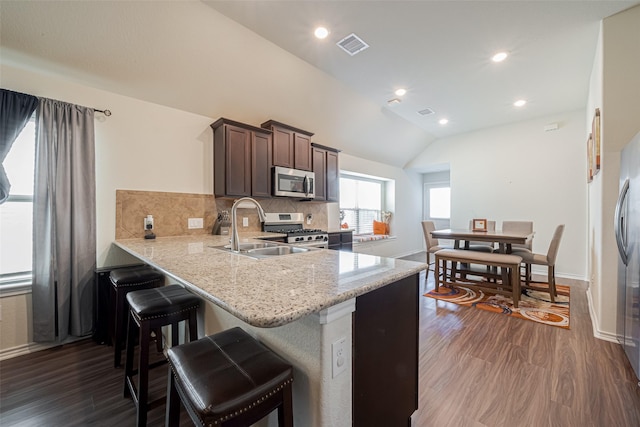 kitchen with stainless steel appliances, a sink, dark wood finished floors, and decorative backsplash