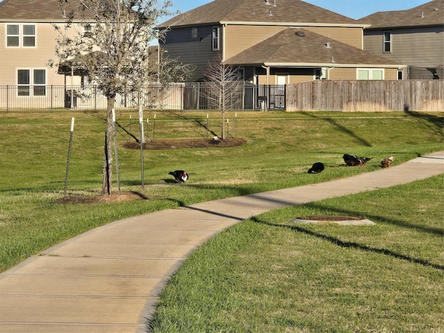 view of home's community with fence and a lawn