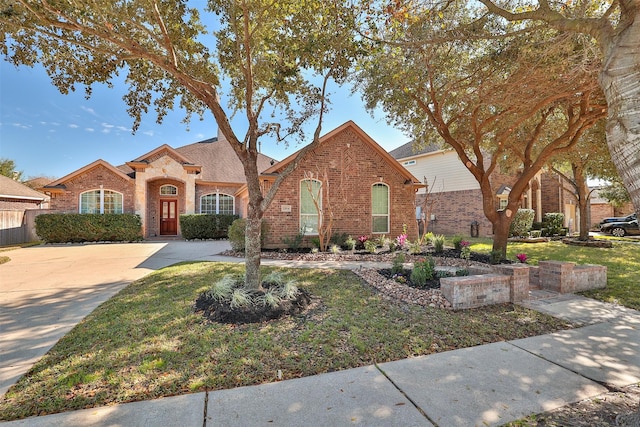 view of front of property with a front lawn, concrete driveway, and brick siding