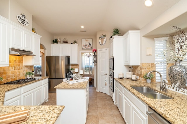 kitchen with stainless steel appliances, white cabinetry, a sink, a kitchen island, and under cabinet range hood