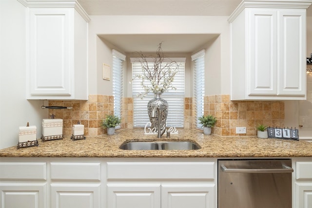 kitchen with tasteful backsplash, stainless steel dishwasher, white cabinetry, a sink, and light stone countertops