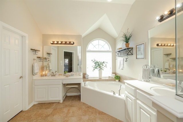 bathroom with vaulted ceiling, a sink, two vanities, and a garden tub