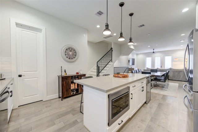 kitchen with open floor plan, stainless steel appliances, visible vents, and white cabinetry