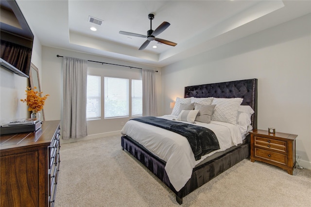 bedroom with recessed lighting, light colored carpet, visible vents, baseboards, and a tray ceiling