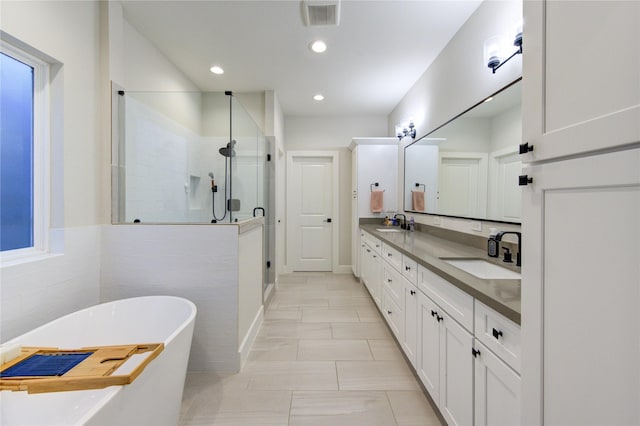 bathroom featuring a soaking tub, a shower stall, visible vents, and a sink