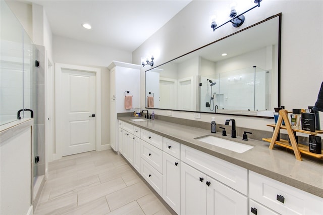 bathroom with double vanity, a shower stall, a sink, and recessed lighting