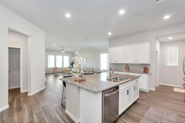 kitchen featuring tasteful backsplash, an island with sink, light wood-type flooring, stainless steel dishwasher, and a sink