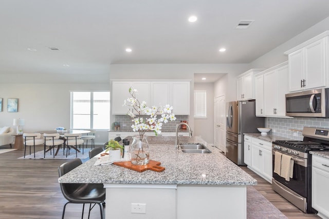 kitchen with visible vents, appliances with stainless steel finishes, white cabinets, a sink, and a kitchen breakfast bar