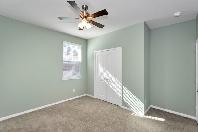 spare room with a ceiling fan, carpet, and baseboards