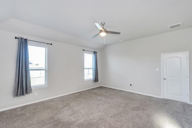 carpeted empty room with lofted ceiling, baseboards, visible vents, and a ceiling fan