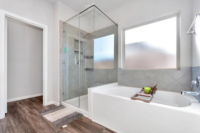 full bathroom with a garden tub, wood finished floors, a shower stall, and baseboards