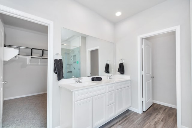 full bathroom with a stall shower, a sink, a spacious closet, and baseboards