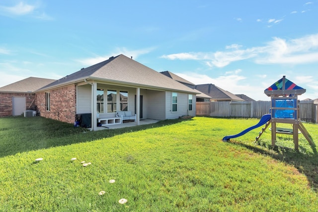 back of house featuring a playground, a yard, brick siding, a patio area, and a fenced backyard