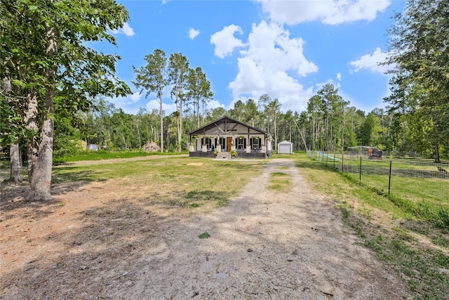 view of front of home with a porch, fence, a shed, driveway, and an outdoor structure