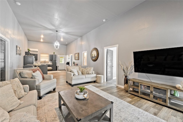 living area with a chandelier, baseboards, and light wood finished floors