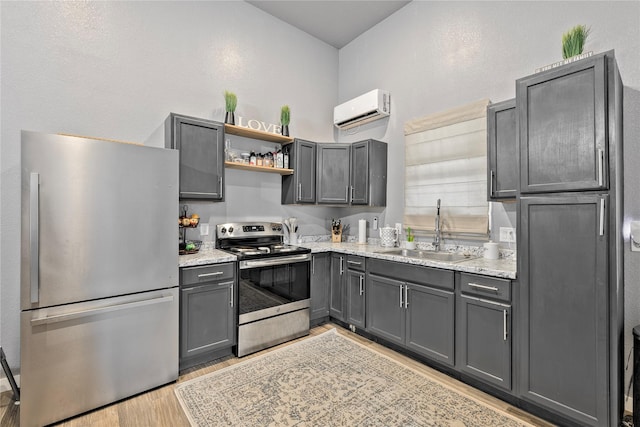 kitchen with light wood finished floors, open shelves, stainless steel appliances, an AC wall unit, and a sink