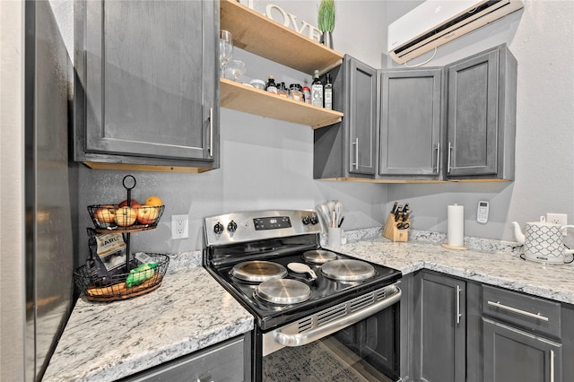 kitchen with light stone counters, open shelves, gray cabinets, an AC wall unit, and stainless steel electric range