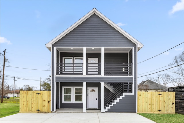 view of front facade featuring a gate, fence, a balcony, and stairs