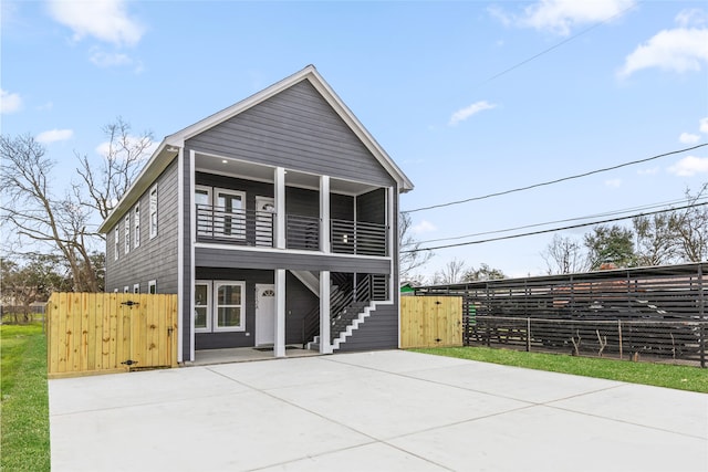 view of front of home featuring a patio, a balcony, fence, stairway, and a gate