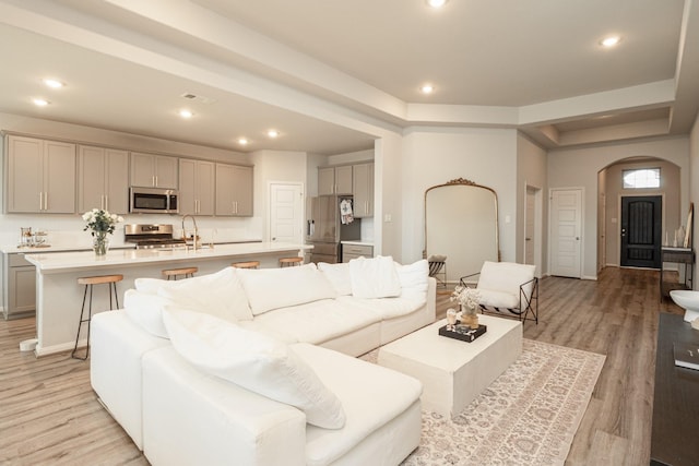 living area featuring arched walkways, light wood finished floors, and recessed lighting