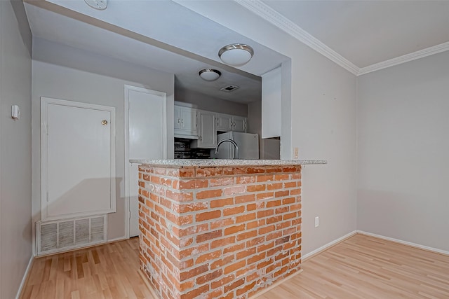 kitchen with freestanding refrigerator, visible vents, and light wood-style floors