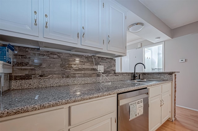 kitchen with a sink, dark stone countertops, decorative backsplash, and stainless steel dishwasher