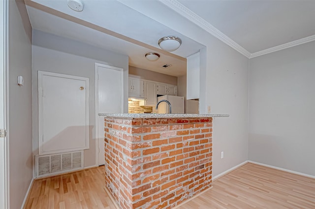 interior space with light wood finished floors, visible vents, white cabinets, freestanding refrigerator, and crown molding