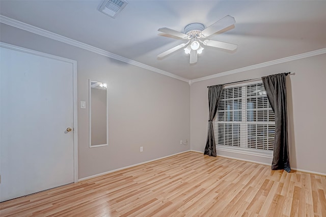 spare room with visible vents, ornamental molding, wood finished floors, and a ceiling fan