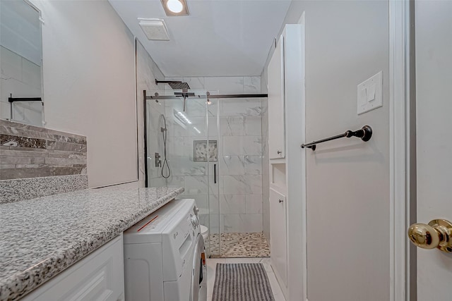 bathroom with washing machine and dryer, visible vents, and a marble finish shower