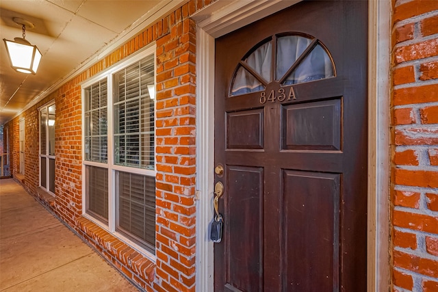 view of exterior entry with covered porch and brick siding