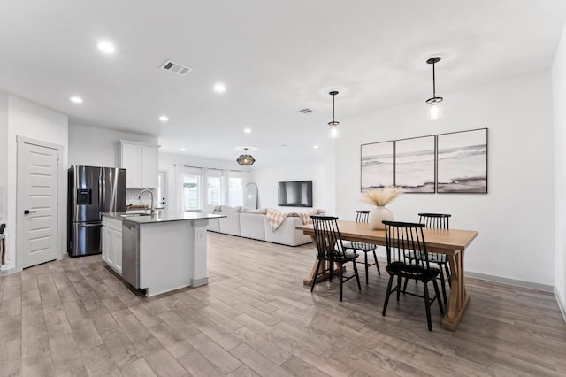 13220 Lago Acero Ln, Texas City, TX 77568 - kitchen featuring stainless steel appliances, open floor plan, light wood finished floors, recessed lighting, and white cabinetry
