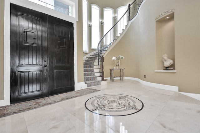 entrance foyer featuring stairs, marble finish floor, and baseboards